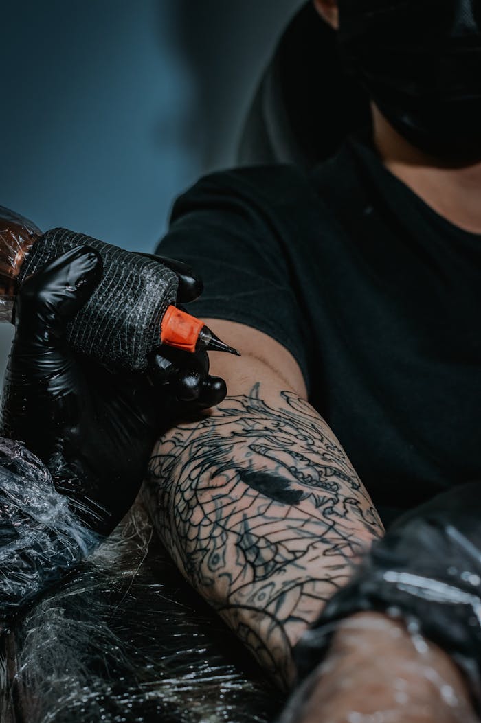 Close-up of a tattoo artist working on an intricate arm design in Bogotá.